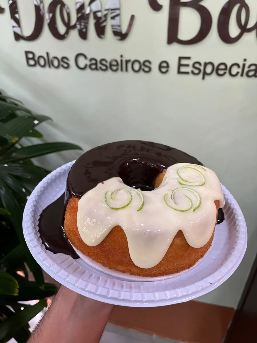 Bolo da Dom Bolo em frente à parede com o nome da loja